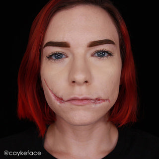 Red-haired model with a scar effect around her mouth, demonstrating Mehron Rigid Collodion.