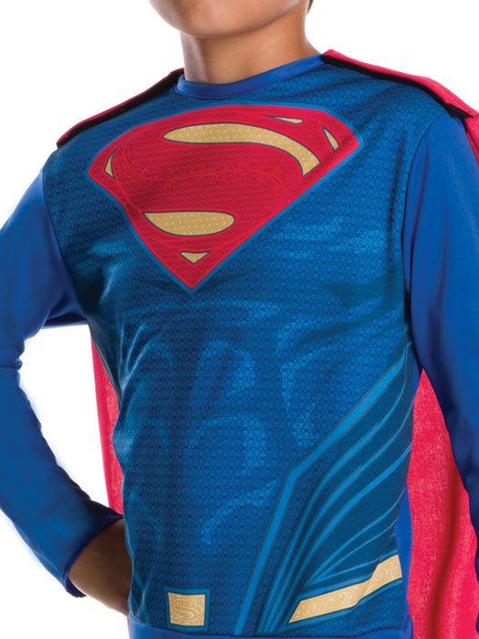 Close-up of the blue Superman jumpsuit with a red-and-yellow chest emblem and red cape.