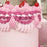 Close-up of pastel pink cake with layered pink piping and cherry decorations