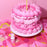 Pink cake with piped ruffles and flowers beside a Colour Mill Candy bottle