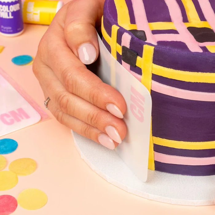 Colour Mill Flexi Scraper curved around the side of a decorated cake