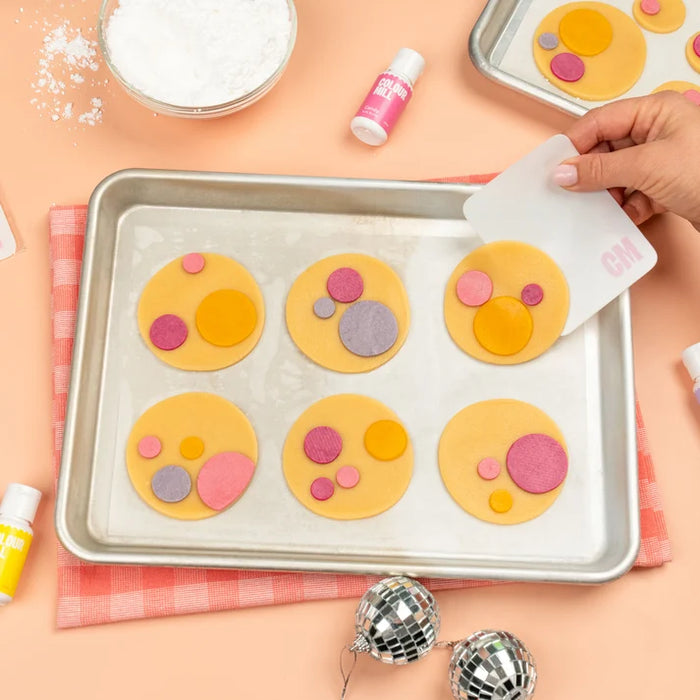 Colour Mill Flexi Scraper lifting a round cookie from a baking tray
