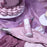 Colour Mill Mauve Oil Blend bottle on mauve icing piping bags beside a decorated cake