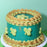 Teal cake with mustard-coloured piped borders and light green butterfly decorations
