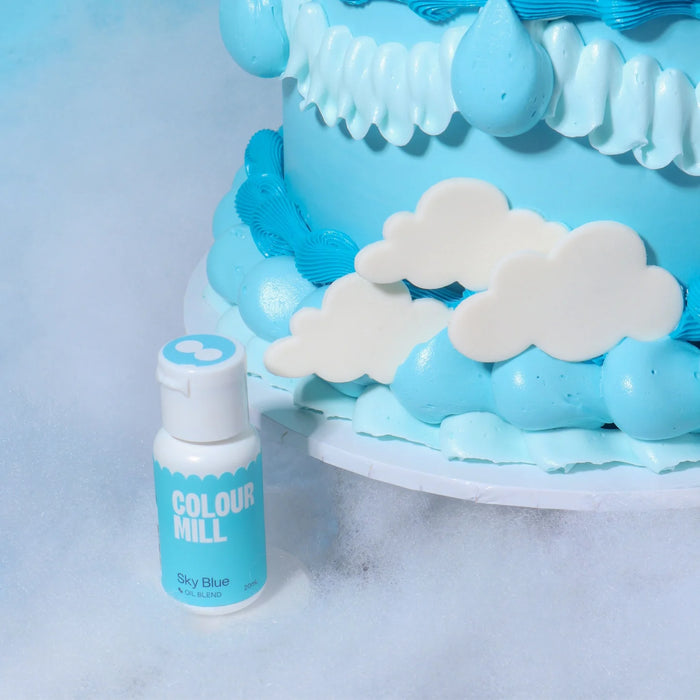 Colour Mill Sky Blue bottle beside blue cake piping and white cloud decorations