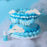Blue piped cake with white cloud decorations beside Colour Mill Sky Blue food colour