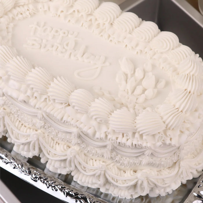 White cake with intricate piped icing on a silver tray