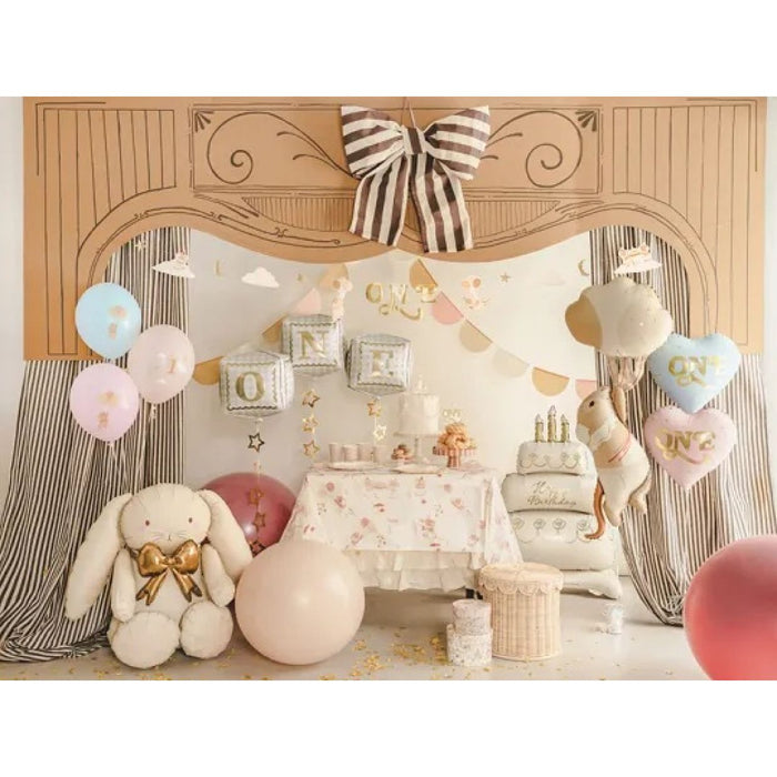 First birthday display with pink ONE heart foil balloon beside a cake table
